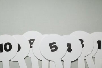 Auction paddles with numbers on light grey background, flat lay. Space for text