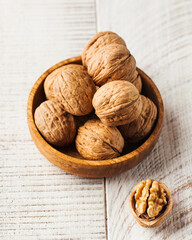 Walnuts in a shell in a wooden plate on a light wooden background. Nuts.