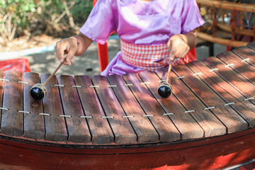 Asian boy play xylophone instrument music performance in ceremony. Wooden xylophone called ranat is...