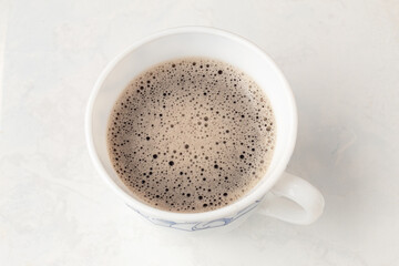 Top view of a cup of foamy coffee isolated on a white background. Small ceramic mug. Break Time.
