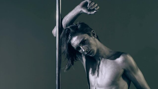 Flexible man exercises on pylon. Sexy flexible man demonstrates sexy flexible body. Flexibility stretching. Flexible female body. Pole dance. Male stripper. Strip dance, man pole dancing.