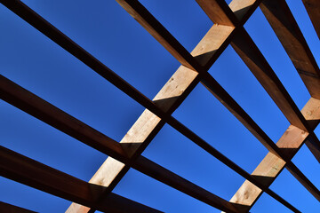 Geometrical shape made of brown wooden board on a dark blue sky.