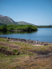 Connemara landscape, lake and mountains in Ireland. Girl walking on the right. Shot in 2023.