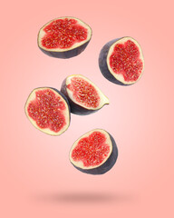 Halved fresh figs falling on coral color backrgound