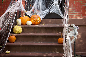 seasonal halloween decorations on steps of a front door with heirloom pumpkins, bones, and cobwebs