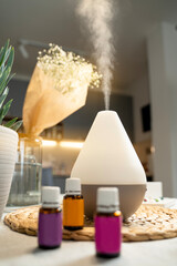 Air diffusor standing on kitchen table, air purification concept, essential oils in bottles next to it 