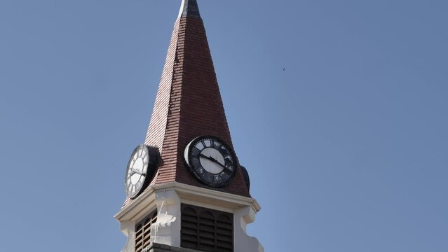 Tilt up stone church clock tower steeple against blue sky, copy space