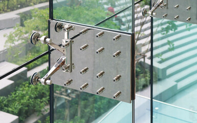 Stainless steel splice plate with spider fittings installed on vertical glass fin structure wall.