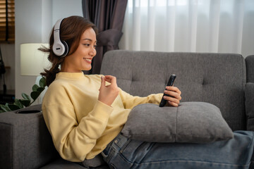 Asian woman sit on the sofa in the living room at home to enjoy their favorite songs.  girl wears...