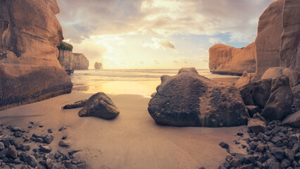 Dramatic sandstone coastline, with rocks and sandy bays and inlets at sunrise in South Island, New...