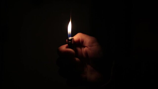 male hand flickering a lighter in a dark room