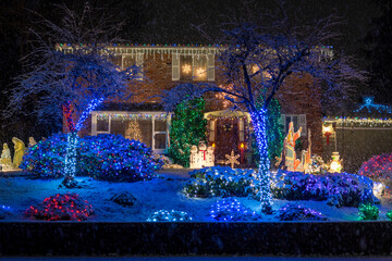 Beautiful Christmas decorations outside the house at night. House decorated with blue lights and snowmen for Christmas. Selective focus, blurred background