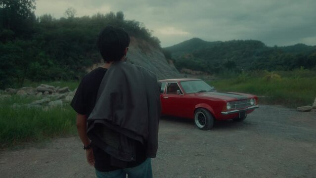 A brutal tomboy girl in a brown leather jacket walks to her classic red car