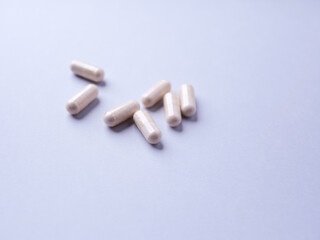 Creatine capsules on bright paper background. Soft focus. Close up. Copy space. 