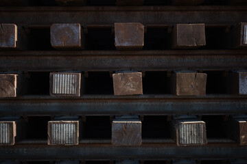 A stack of wooden beams and steel railroad tracks at a depot alongside a railroad route in California. The materials express themes of rail infrastructure, as well as a geometric array of commodities.