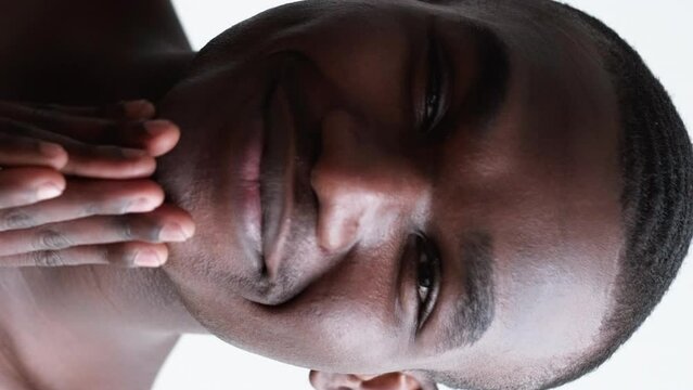 Vertical video. Male wellbeing. Hygiene treatment. Facial skincare. Confident cheerful shirtless man touching shaved smooth face skin smiling isolated on white background.