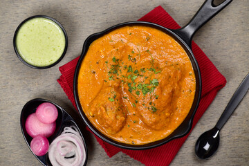 Top view of butter chicken with onion and mint chutney