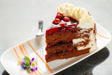 Black forest gateaux cake with a chocolate sponge, cherry compote, and Chantilly cream. Decorated with chocolate flakes.
