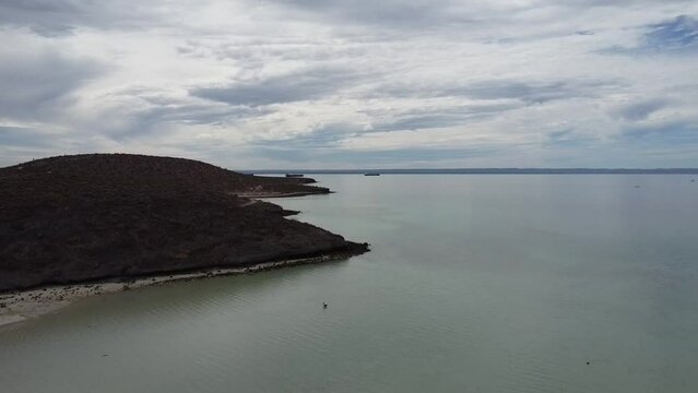 Ascending aerial view of a beautiful coastline overlooking the dry landscape of Playa El Tecolote in Baja California Sur, Mexico during a great trip