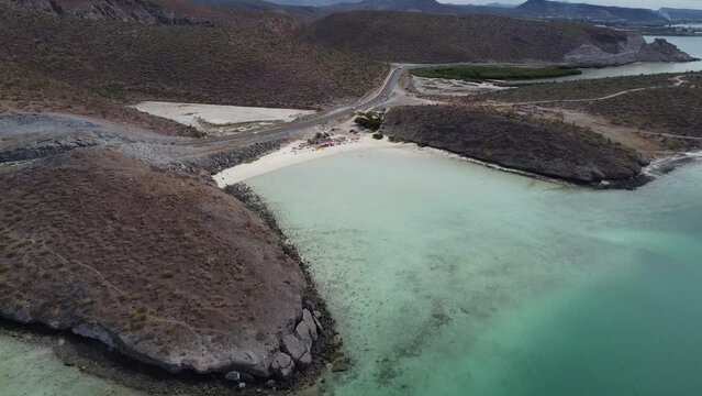 Aerial shot of a gorgeous coastal area with turquoise calm sea, coastal road and dry landscape in Playa El Tecolote near La paz Baja California Sur Mexico