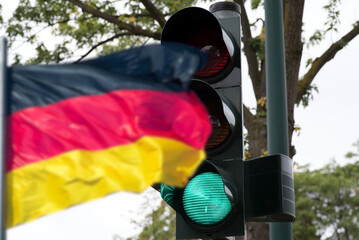 Flagge von Deutschland und eine Ampel, die auf Grün steht