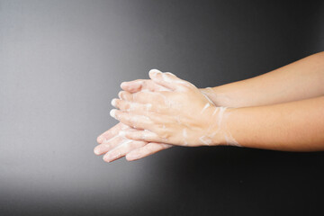 Washing hands with hand wash on dark background