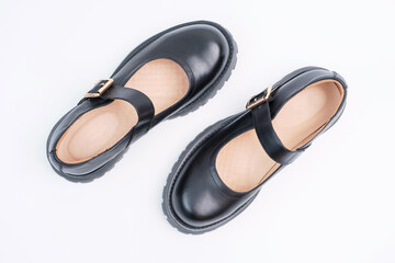 Pair of female black leather shoes on background close-up top view.