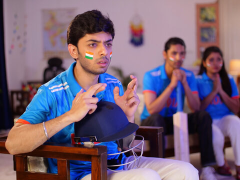 Cricket fans watching a live match at home - Praying for the victory of an Indian cricket team  female cricket fan. Siblings engrossed in watching a live cricket match on a large-screen television ...