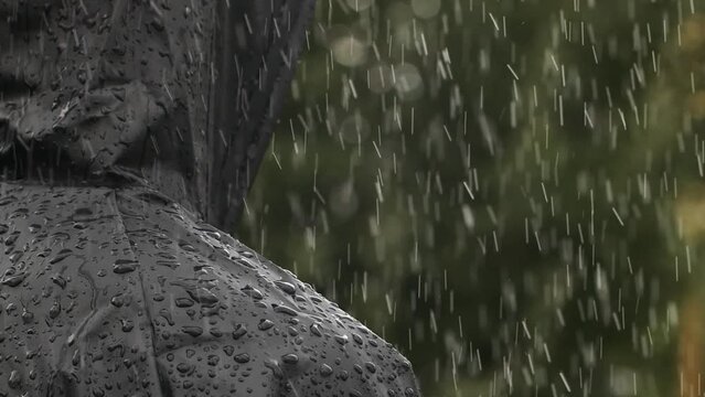 Closeup unrecognizable person in heavy rain, young man in water proof black coat