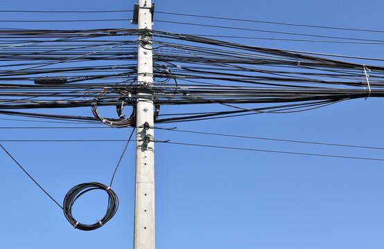 messy electrical wire and telecom cables on concrete electric pole with clear sky