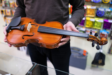 seller demonstrates a violin in a music store