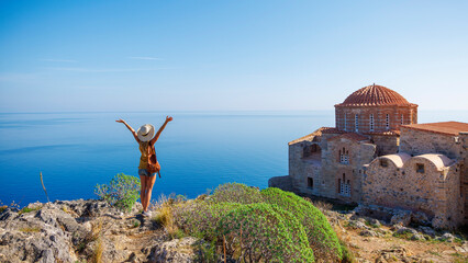 Fototapeta premium Traveler caucasian woman in Greece- typical orthodox church and mediterranean sea