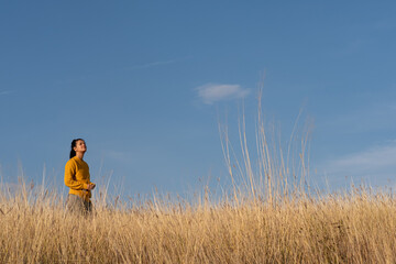 Naklejka na ściany i meble Young woman hiking through autumn fields and hills against blue sky during warm day. Weekend, leisure, sport