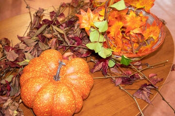 carved halloween pumpkins on table and leaves sitting in a row on wooden background