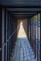 An improvised visual tunnel made of a metal fence along the roadway with wooden flooring.