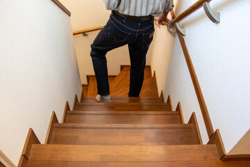 手すりを握りながら階段を降りる男性