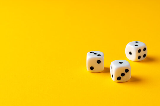 Three dice cubes on yellow background close up