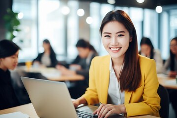 Fototapeta premium Portrait of young woman working on laptop computer in modern office, Confident employee smiling happily while working with coworkers.