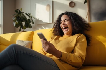 Happy excited young woman relaxing on couch using mobile phone winning in online app game. Young lucky girl feeling winner looking at cellphone, receiving great news or discount offer. - obrazy, fototapety, plakaty