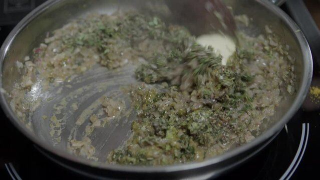 Close-up of a chef mixing ingredients in a metal pan. Preparing a delicious caf&eacute; de paris sauce for steaks. No face.