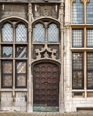 Brown wooden door leading to an old building with windows in Grote Markt, Antwerp, Flanders, Belgium