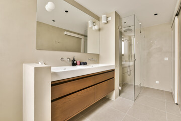 a modern bathroom with wood cabinets and white counter tops, including a large mirror on the wall above the sink