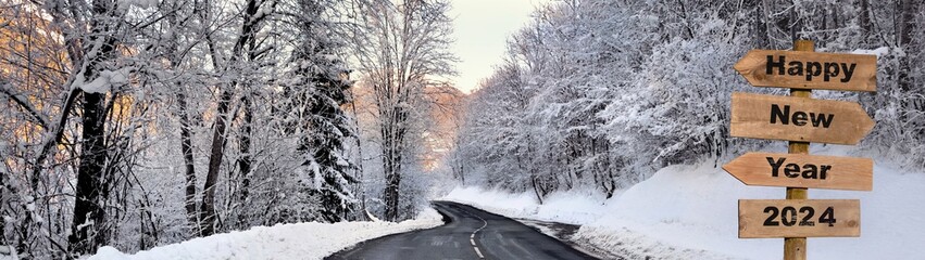 2024 happy new year written on wooden directional sign post to a road crossing a snowy forest in alpine mountain © coco