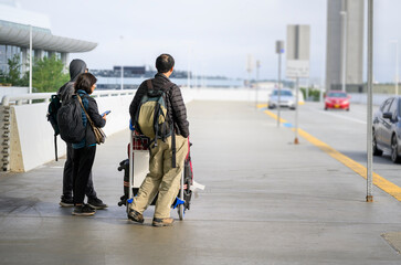 Passengers with luggage trolleys waiting for the pickup at an airport. USA. © Janice
