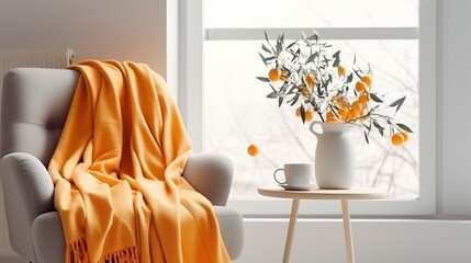 A cozy modern armchair with a soft orange blanket and a coffee table with a vase against the backdrop of a large window