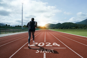 Happy New Year 2024 symbolizes the start of the new year. Woman preparing to run on the athletics track is engraved with the year 2024. start challenge goal of planning health and business to success - obrazy, fototapety, plakaty