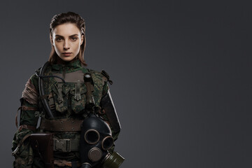 Confident female soldier in military attire posing against a gray backdrop, representing the Middle East conflict