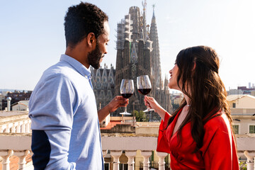 Multiracial beautiful happy couple of lovers dating on rooftop balcony at Sagrada Familia,...