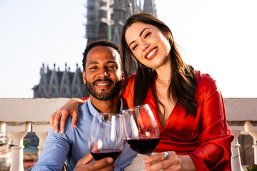 Multiracial beautiful happy couple of lovers dating on rooftop balcony at Sagrada Familia,...
