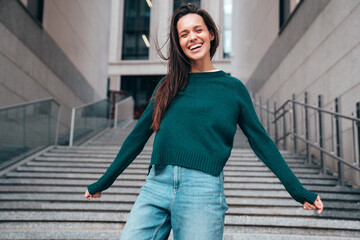 Street fashion portrait of beautiful caucasian woman walking outdoors. Beautiful young model in warm sweater. Fashion stylish pretty female posing in the street, having fun in city